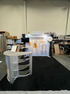 RENTAL: RE-1023 Design with Extrusion Backwall, Arch Header Frame, (2) LED Arm Lights, ECO-4C Reception Counter, Tension Fabric Graphics, and Direct Print Sintra Graphics