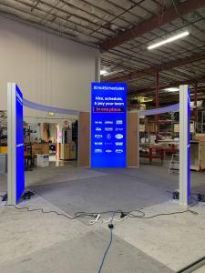RENTAL: Modified RE-9146 Island Design with (1) 5' Wide x 12' High Lightbox, (2) 4' Wide x 8' High Double-Sided Lightboxes, Curved Frosted Acrylic Wing Panels, Storage Closet with Locking Door, (4) Large Monitor Mounts, Backlit SEG Fabric Graphics, and Di
